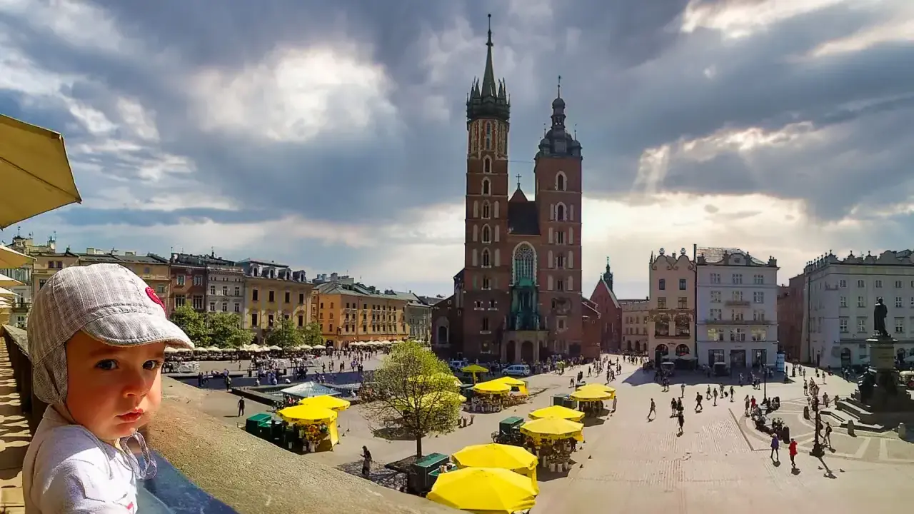 Małe dziecko w czapce patrzy na Rynek Główny w Krakowie. Idealne miejsce na wycieczkę z dziećmi.