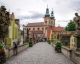 Kamienny most z rzeźbami i barokową architekturą, w tym kościołem z zielonymi kopułami. To piękne ziemia kłodzka atrakcje.