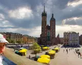 Małe dziecko w czapce patrzy na Rynek Główny w Krakowie. Idealne miejsce na wycieczkę z dziećmi.