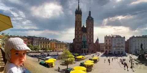 Małe dziecko w czapce patrzy na Rynek Główny w Krakowie. Idealne miejsce na wycieczkę z dziećmi.