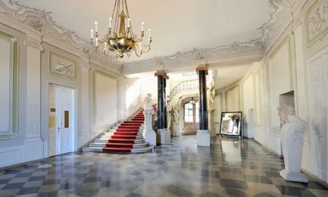 Elegancka klatka schodowa z czerwonym dywanem w Pałacu Branickich w Białymstoku. Sprawdź cennik zwiedzania!
