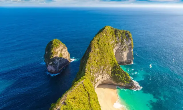 Nusa Penida, idealne miejsce na Twój **bali plan zwiedzania**. Klify porośnięte zielenią, turkusowa woda i piaszczysta plaża.