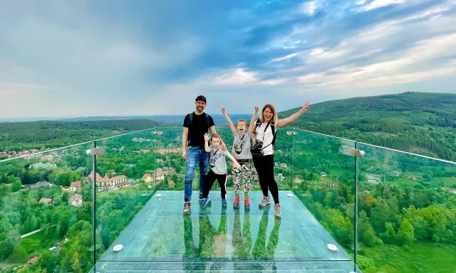 Rodzina cieszy się spacerem w chmurach w Szklarskiej Porębie. Szklany taras widokowy oferuje zapierający dech w piersiach widok na zielone wzgórza i miasteczko.