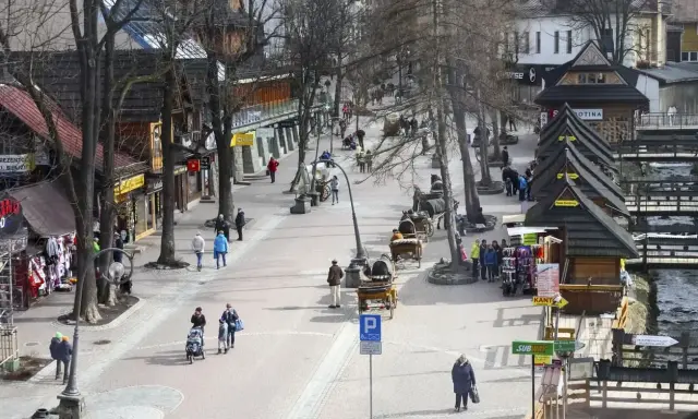 Spacer po tętniącym życiem centrum Zakopanego, z dorożkami i ludźmi przechadzającymi się po deptaku.