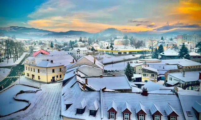 Zimowy krajobraz miasta w Czechach, z ośnieżonymi dachami i wzgórzami w tle. Idealne miejsce na odkrywanie atrakcji przy granicy.