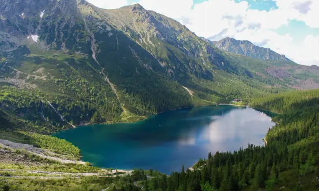 Morskie Oko, największe jezioro w Tatrach, otoczone stromymi, zielonymi zboczami gór i lasami.