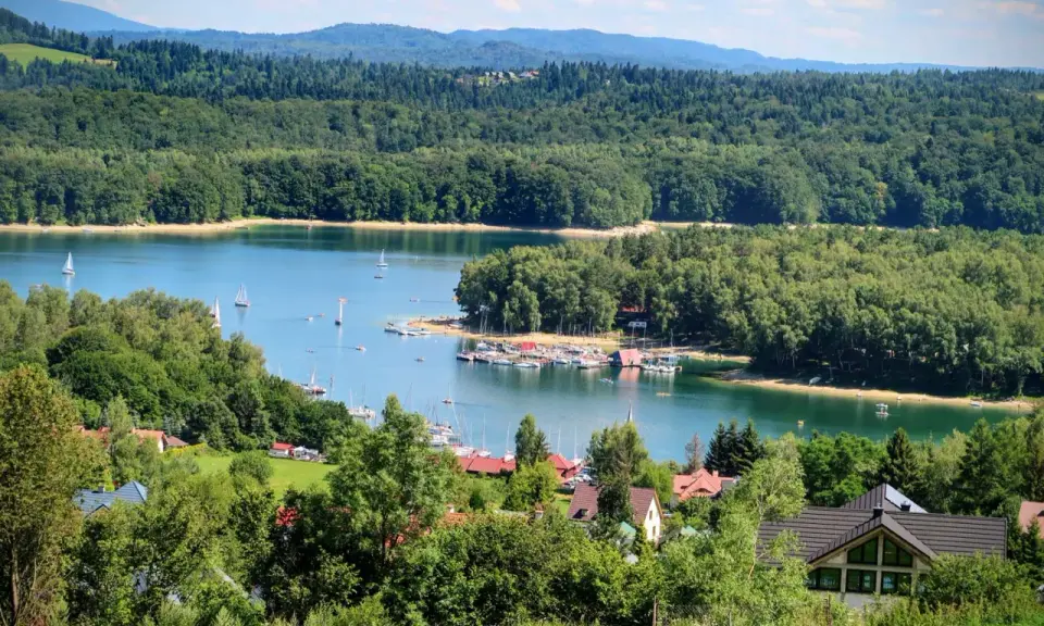 Malownicze miejscowości nad Soliną, z żaglówkami na turkusowej wodzie i zielonymi wzgórzami w tle.