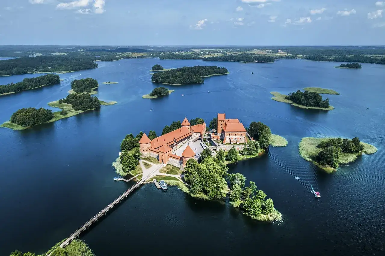 Malowniczy zamek na wyspie, połączony mostem z lądem. Wokół jezioro z licznymi wysepkami, tworzące piękne Trakai atrakcje.