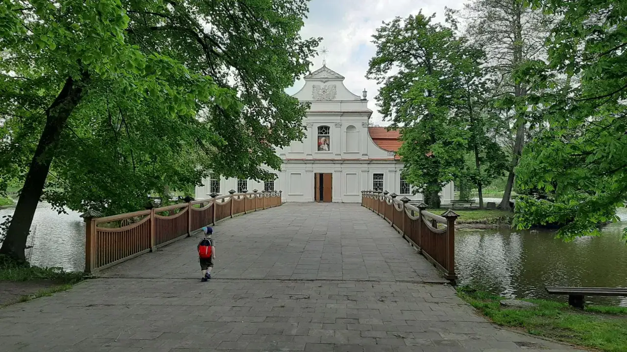 Chłopiec z plecakiem idzie mostem do białego pałacu. To idealne miejsce na zwiedzanie, można tu zaplanować zwiedzanie zwierzyniec.