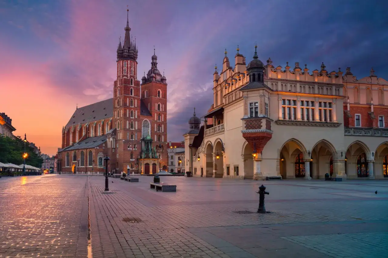 Zachód słońca nad Rynkiem Głównym w Krakowie. Bazylika Mariacka i Sukiennice w blasku purpurowego nieba. Ciekawe miejsca w Krakowie czekają!